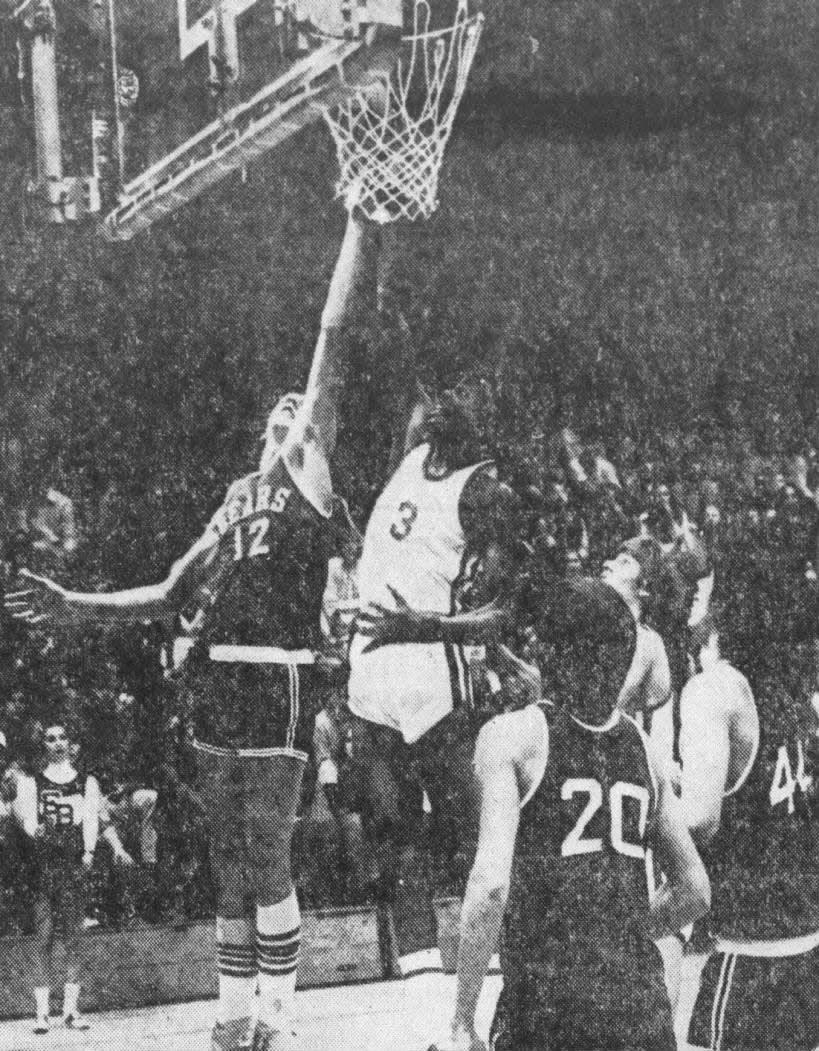 Mike McSween (12) of East Brunswick, stretches beyond the reach of Chad Kinch of Perth Amboy to score a field goal in the second period of the game on Thursday, Jan. 10, 1974. Watching the action are Jack Bibby (20) and Paul Caubel (44) of East Brunswick. Perth Amboy won 73-62.