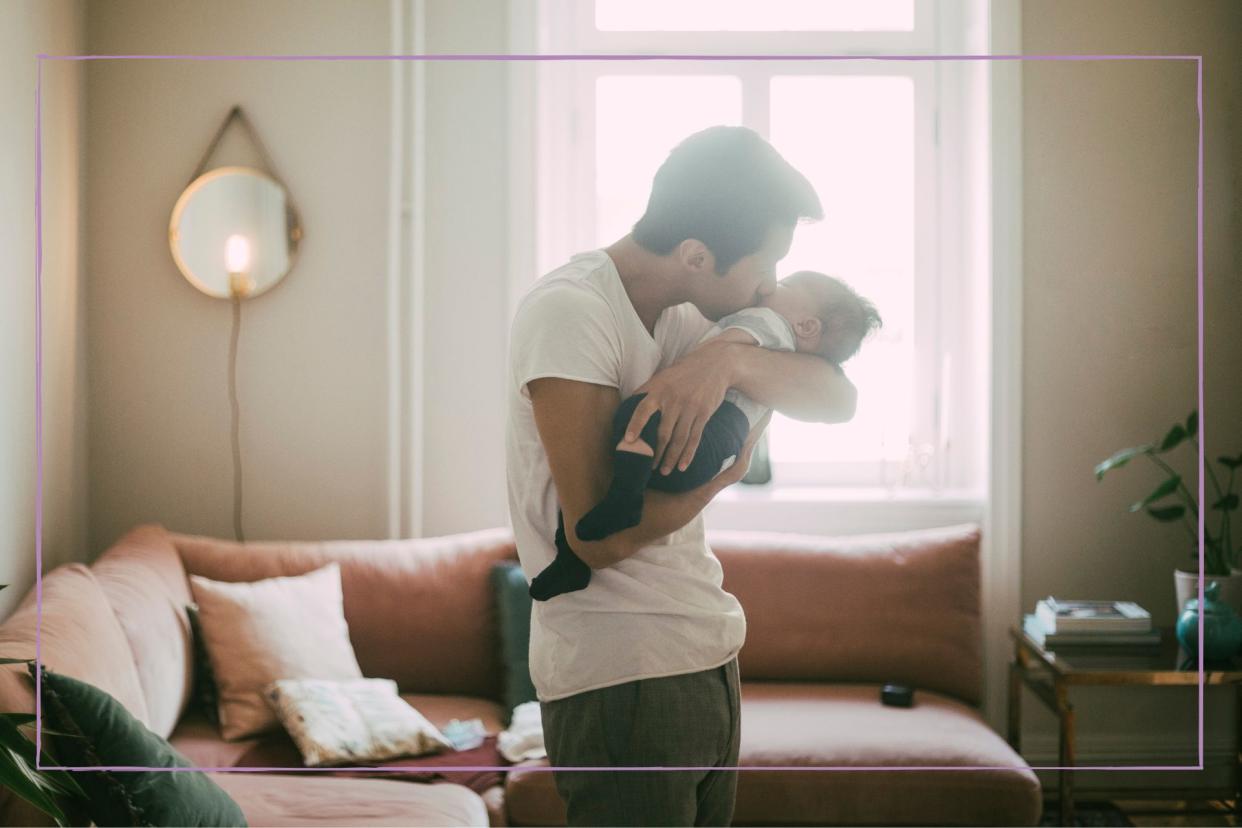  Man holding newborn baby against a bright window 