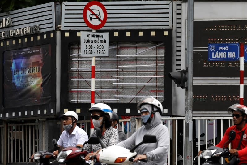 FILE PHOTO: Bikers drive past an empty space where a promotional poster for the DreamWorks film "Abominable" was hanging before being taken down at a cinema in Hanoi