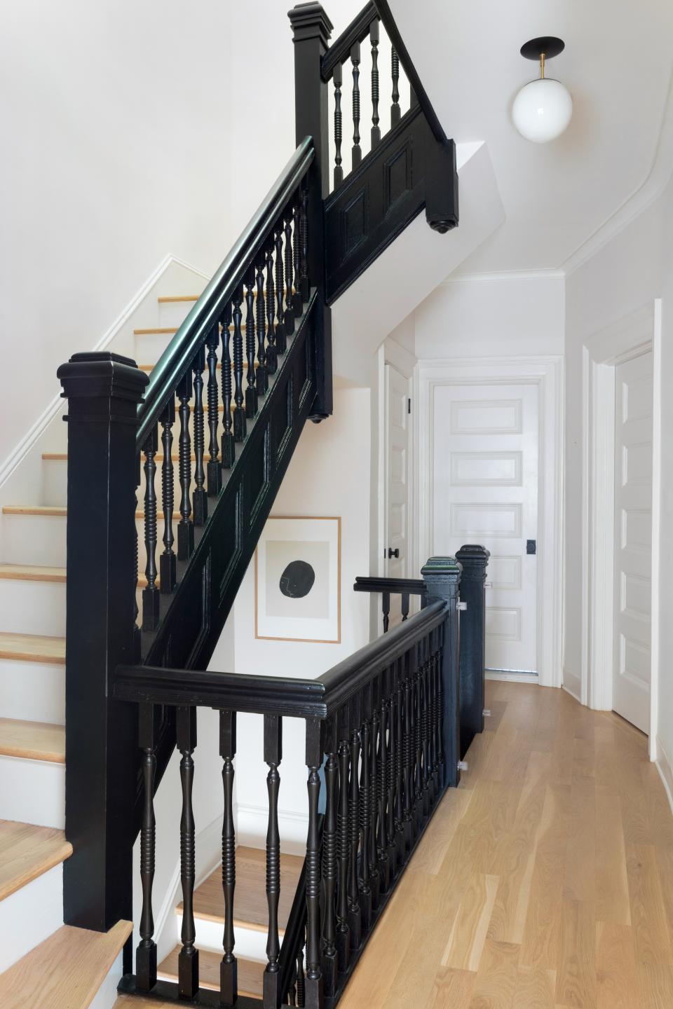 AFTER: “We opened up the bottom of the stair, added new treads to match the white oak floor, and painted the risers and balustrade,” Sheena says. Adds Lisa: “It’s hard to believe it’s the same staircase—black really is slimming!”