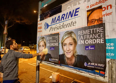 FILE PHOTO: Members of the National Front youths put up posters of Marine Le Pen, French National Front (FN) political party leader and candidate for the French 2017 presidential election, ahead of a 2-day FN political rally to launch the presidential campaign in Lyon, France, February 2, 2017. REUTERS/Robert Pratta/File Photo