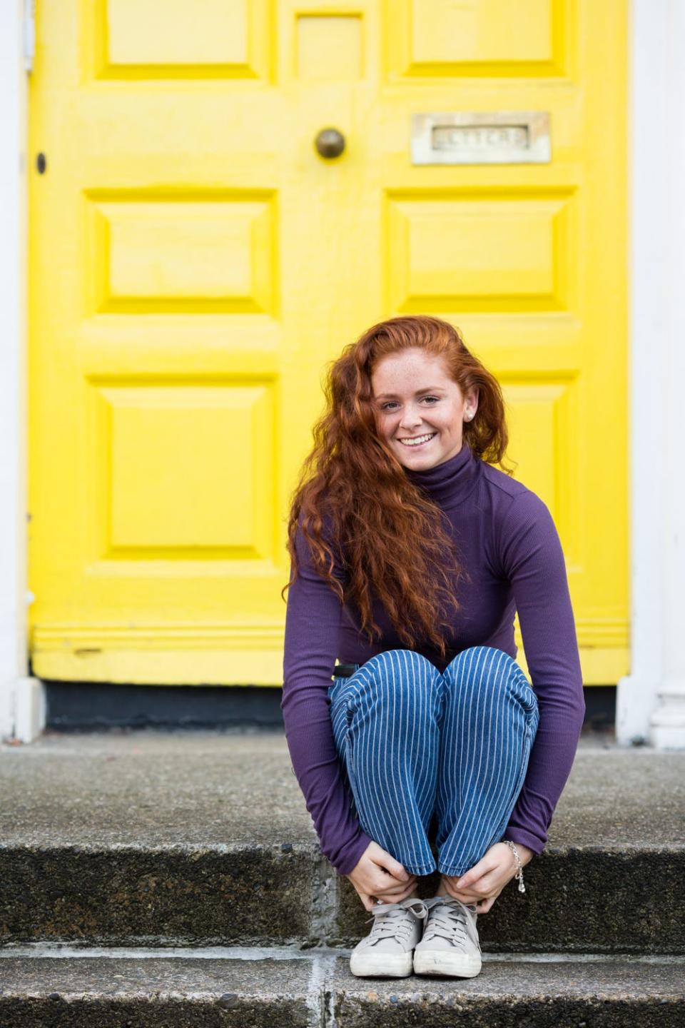 A redheaded model named Alice from Dublin, Ireland, poses against a yellow door