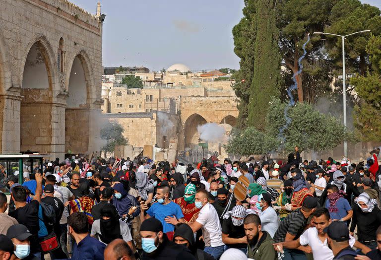 Palestinos correr por protección ante el lanzamiento de gases lacrimógenos por parte de la policía 