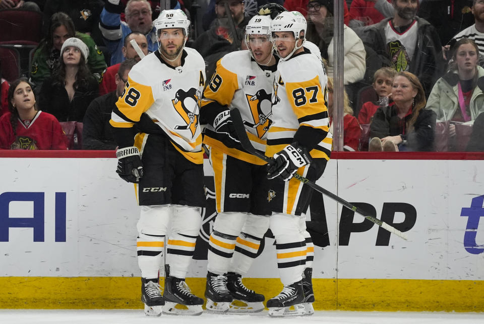 Pittsburgh Penguins defenseman Kris Letang, right wing Reilly Smith and center Sidney Crosby, from left, celebrate Smith's goal against the Chicago Blackhawks during the first period of an NHL hockey game Thursday, Feb. 15, 2024, in Chicago. (AP Photo/Erin Hooley)