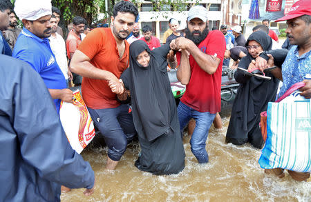 Rescuers help a woman to move through a water-logged road after she was evacuated from a flooded area in Aluva in Kerala, India, August 18, 2018. REUTERS/Sivaram V