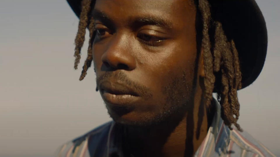 Jonathan Ajayi wearing a hat in the midday sun in The Drifters.