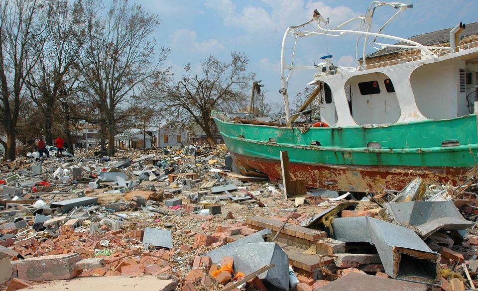Men pick through rubble as a boat sits several hundred yards from the beach in the historic downtown district of Biloxi on Saturday, Sept. 3, 2005. Storm surge from Hurricane Katrina destroyed many of the old buildings in the area.