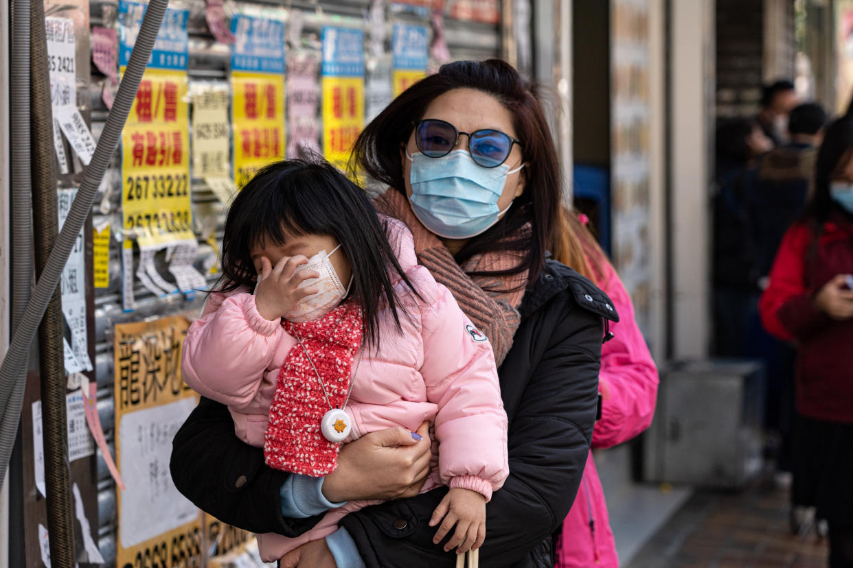 People wearing masks on the street in Hong Kong on January 30, 2020. People queue in line to purchase protective masks outside the store.  (Photo by Yat Kai Yeung/NurPhoto via Getty Images)