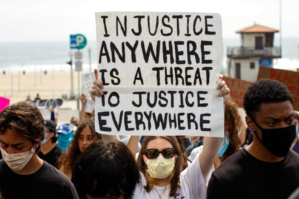 <i>A woman holds up a sign with the Martin Luther King Jr. quote "Injustice anywhere is a threat to justice everywhere" during a protest in Manhattan Beach, California, on June 2.</i>