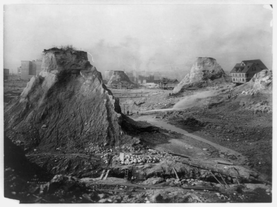 Hilly terrain, gravel roads, and just a few small buildings in a black-and-white photo