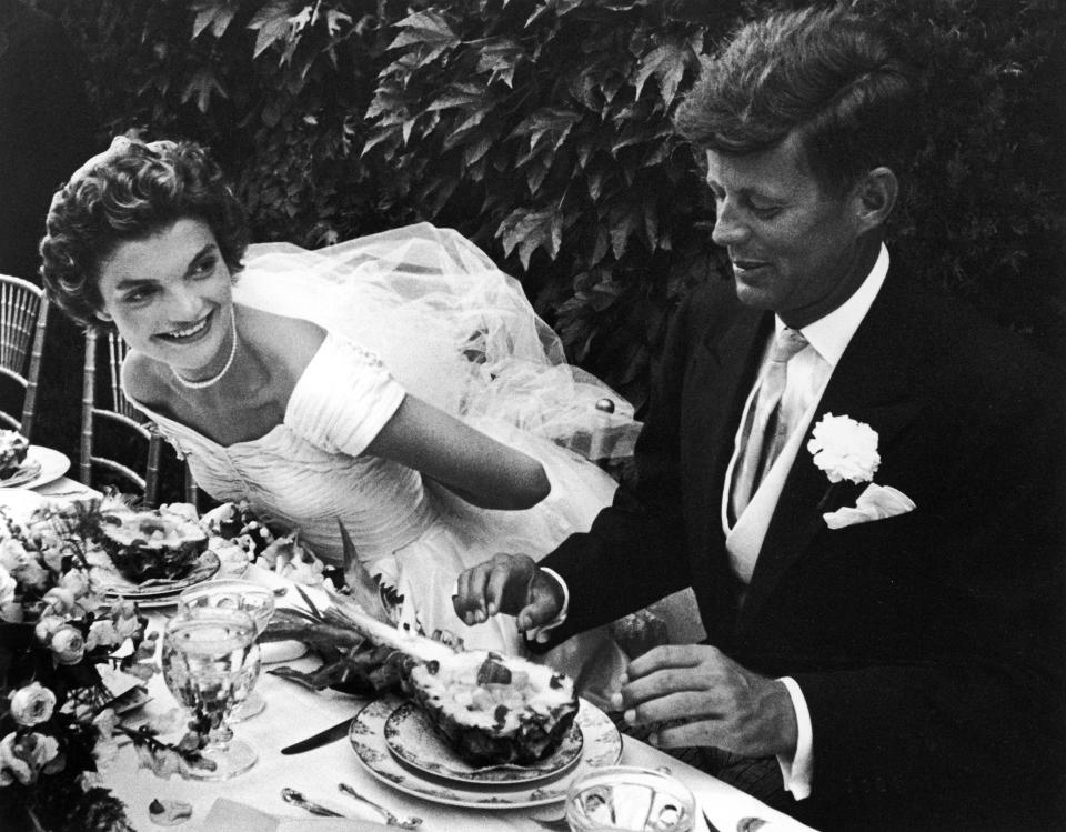 Senator John Kennedy and bride Jacqueline sitting together outdoors at table, eating pineapple salad, at their wedding reception. (Photo by Lisa Larsen/Time & Life Pictures/Getty Images)