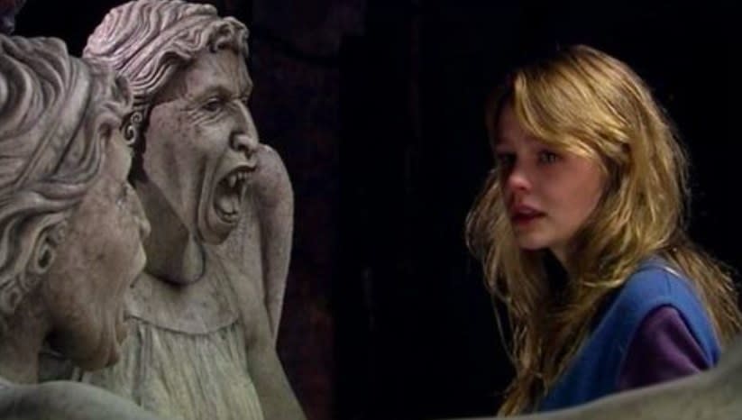 Sally stands in front of two Weeping Angels