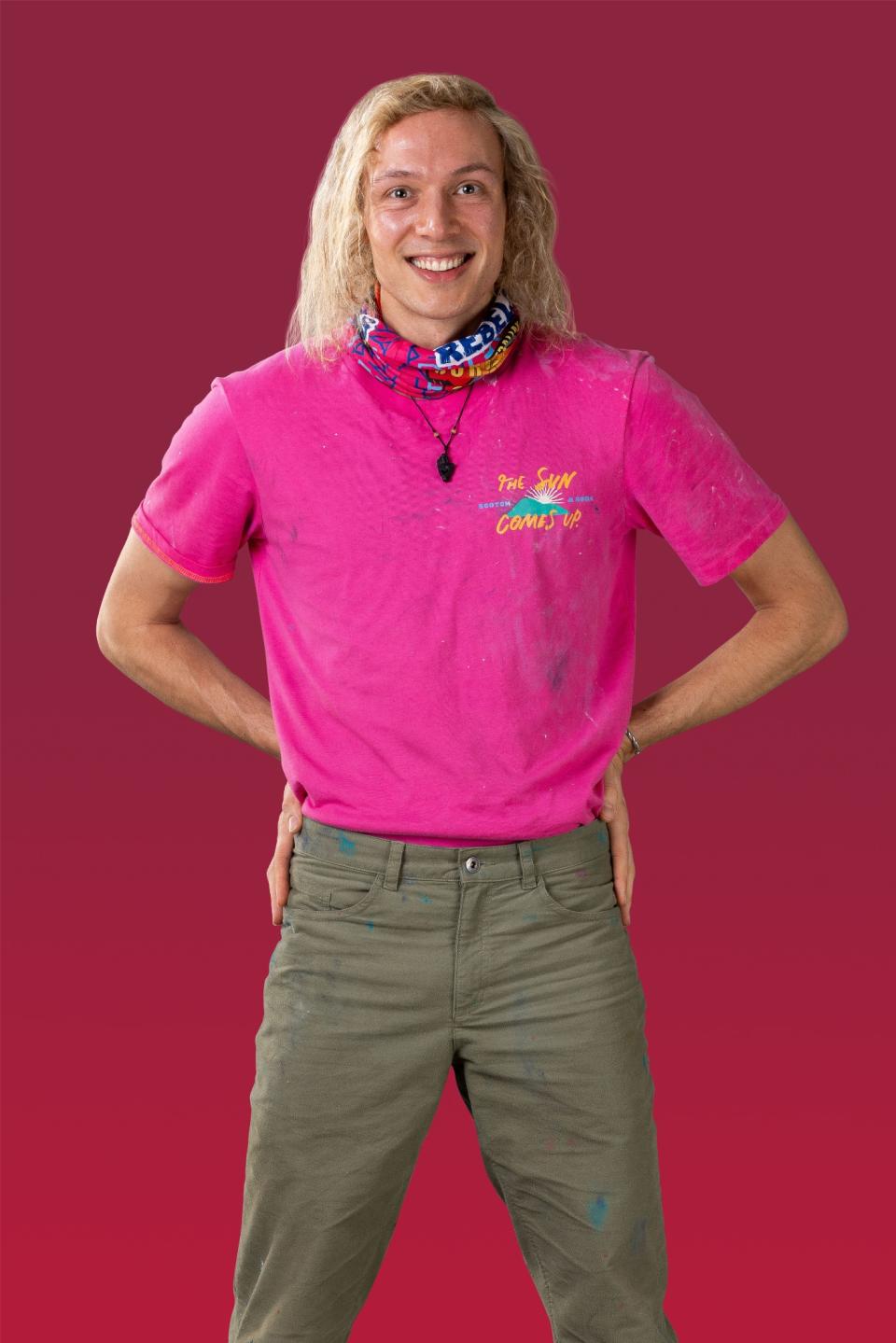 Scott wears a pink t-shirt and smiles at the camera.