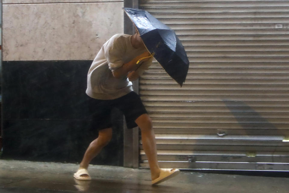 A man with an umbrella struggles against strong wind and rain brought by super typhoon Saola in Hong Kong, on Friday, Sept. 1, 2023. Most of Hong Kong and other parts of southern China ground to a near standstill Friday with classes and flights canceled as powerful Typhoon Saola approached. (AP Photo/Daniel Ceng)