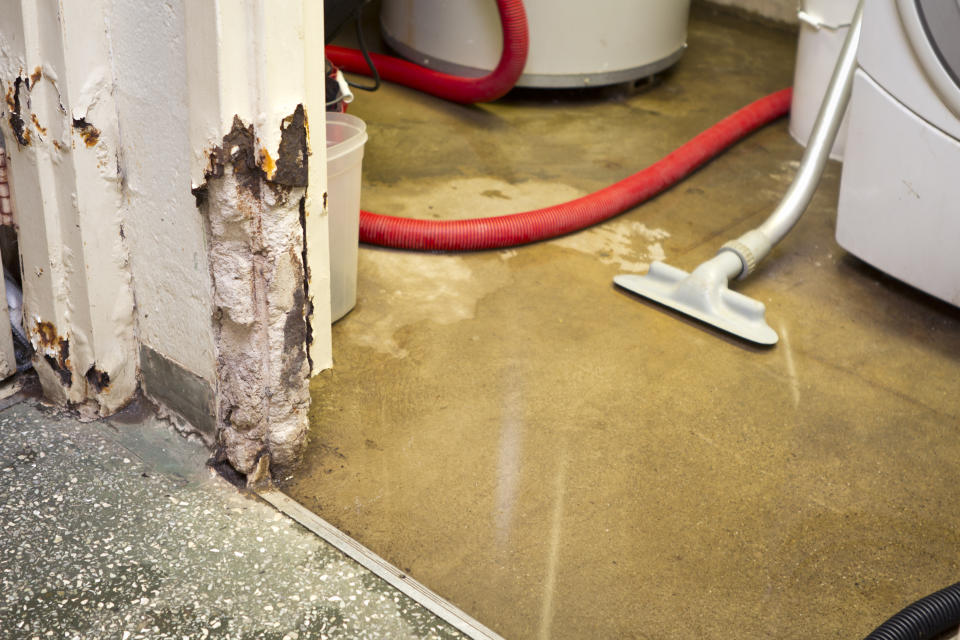 A flooded room with a vacuum sucking water, showing water damage on the wall