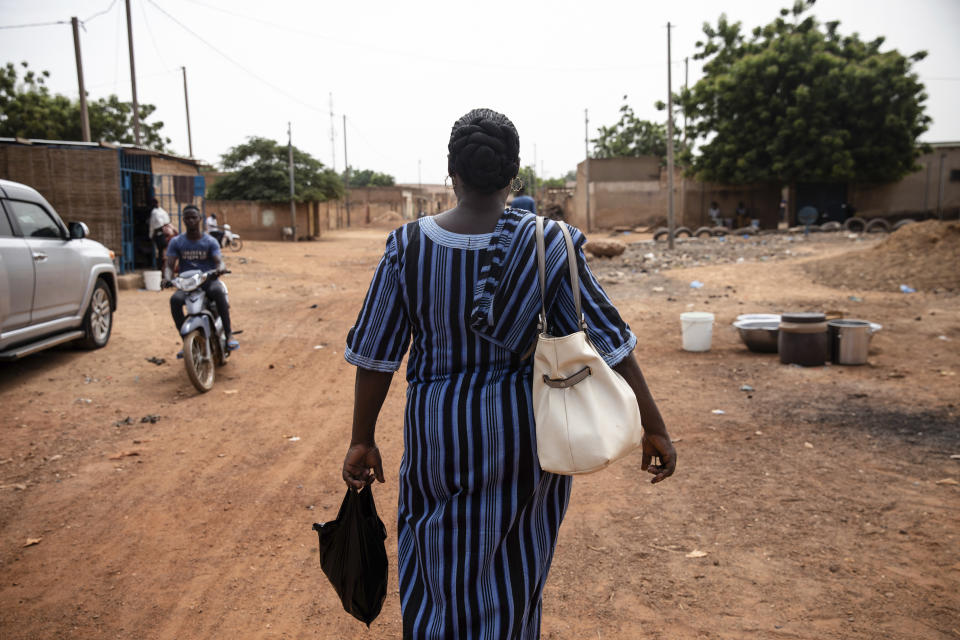 Mariama Sawadogo, 44, who works as a radio host at Zama Radio in Kaya, Burkina Faso, walks back home Monday, Oct. 25, 2021. Many guests and listeners in Burkina Faso call her "aunty" as she gently guides them to the right answers and awards prizes such as soap and washing buckets. In the West African country of Burkina Faso, many feel the government has let them down during the pandemic. Tests, vaccines and messaging often miss many residents, despite a $200 million budget for virus-response efforts. In a region where women are responsible for family work and community relationships, they’ve stepped up to fill in gaps. (AP Photo/Sophie Garcia)