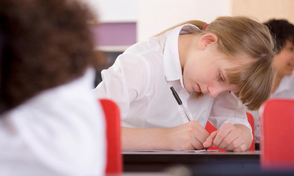 Schoolgirl taking test on desk in classroom.