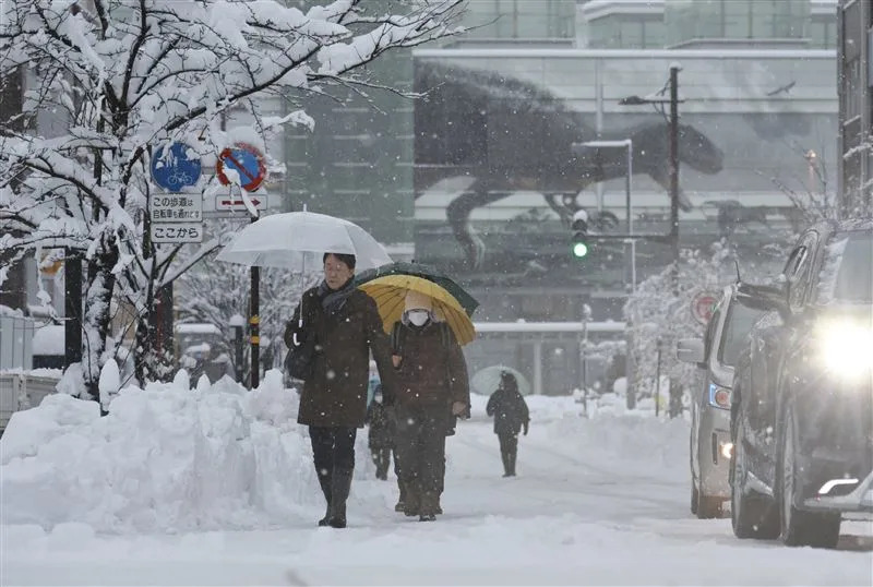 日本氣象廳警告對北陸、新潟縣、東北日本海一帶發出大雪警報，福井市上班族頂著酷寒風雪出門。（圖／美聯社／達志影像）