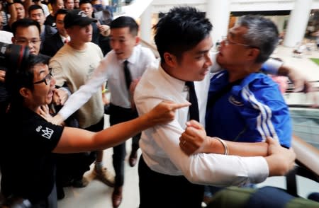 A pro-government and an anti-government protesters shout slogans against each other as security guards try to stop them at Olympian City 2 shopping mall in Hong Kong