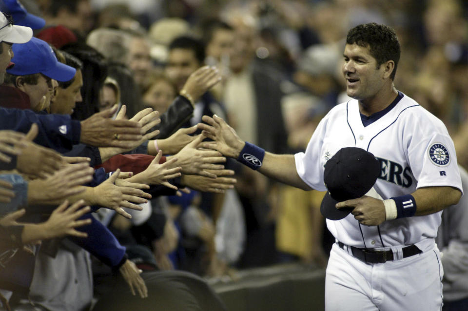 File-This Oct. 2, 2004, file photo shows Seattle Mariners Edgar Martinez high fiving Mariner fans as he runs the track surrounding the infield during Edgar Martinez Day in Seattle. Martinez was a .312 hitter over 18 seasons with Seattle. He got 85.4 percent in his 10th and final try on the writers’ ballot. He and Baines will join 2014 inductee Frank Thomas as the only Hall of Famers to play the majority of their games at designated hitter. David Ortiz will be eligible in 2022. (AP Photo/Jim Bryant, File)