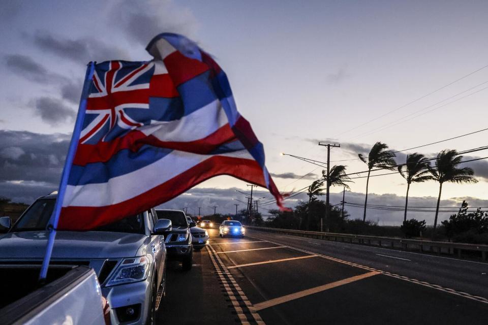 A flag flaps from a car.