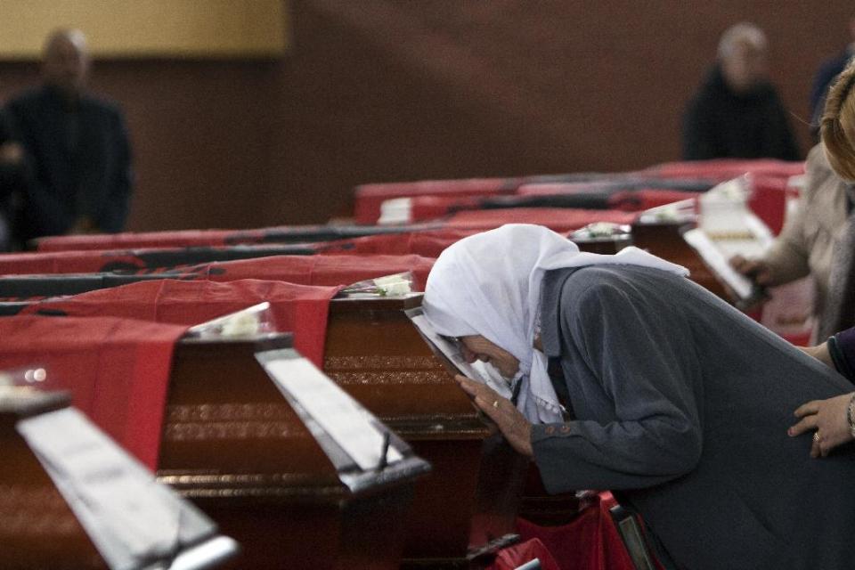 Ethnic Albanian women cry on top of a coffin draped with the Albanian flag containing the remains of ethnic Albanians killed during 1998-99 Kosovo war in the town of Suva Reka during the funeral ceremony on Wednesday, March 26, 2014. The victims were killed in two separate rampages by Serbs forces in town of Suva Reka and Mala Krusa just days after NATO began a bombing campaign to end an onslaught by Serbia on separatist ethnic Albanians. (AP Photo/Visar Kryeziu)