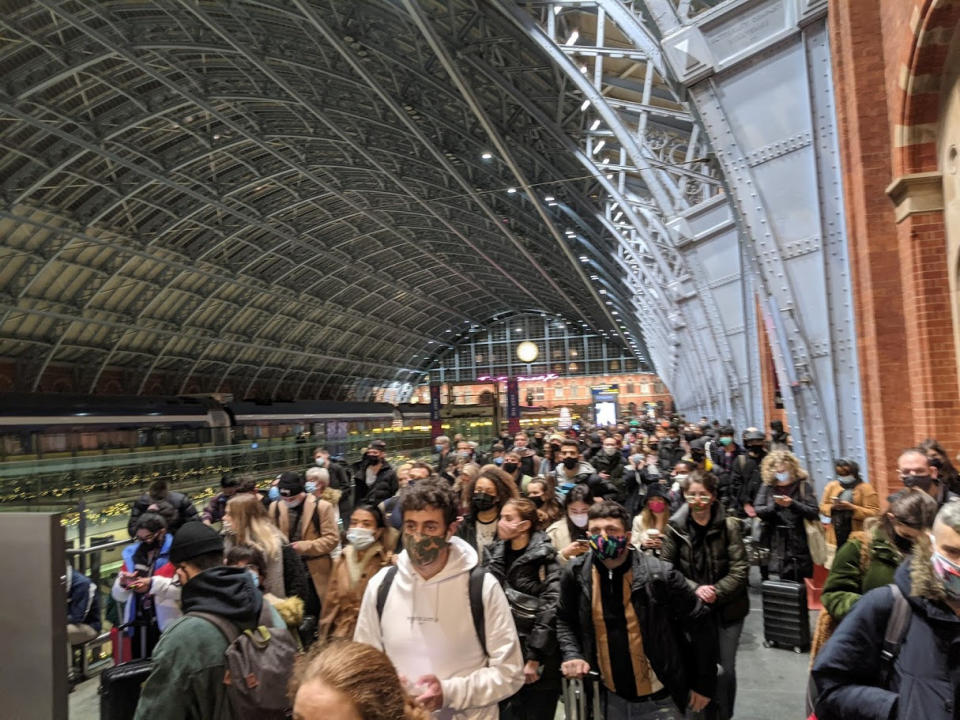 These shocking images show St Pancras train station packed with masked passengers desperate to get home for Christmas before Tier 4 restrictions hit London. See SWNS story SWOCtrain. Masked passengers can be seen clutching suitcases as they stand shoulder to shoulder with other ticket holders, rendering social distancing impossible. The shocking sight was filmed around three hours after Prime Minister Boris Johnson announced that London and areas in South East England would be entering Tier 4 yesterday afternoon [December 19]. With restrictions hitting the capital city at midnight last night, hundreds rushed to train stations in a desperate attempt to get home for Christmas.    