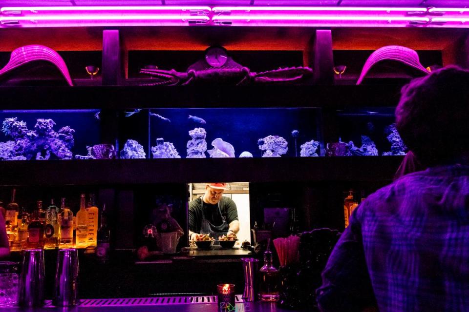 Chef Josh Elliott serves orders through the window under the fish tank above the bar at Brother’s Keeper.