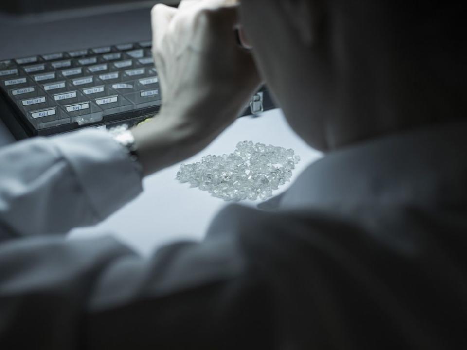 A worker evaluates diamonds under subdued lighting at Alrosa's sorting center in Mirny, Russia.