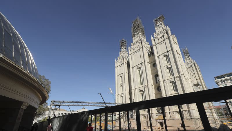 Visitors to Temple Square watch as renovation work takes place on the Salt Lake Temple in Salt Lake City on Saturday, Oct. 17, 2020.