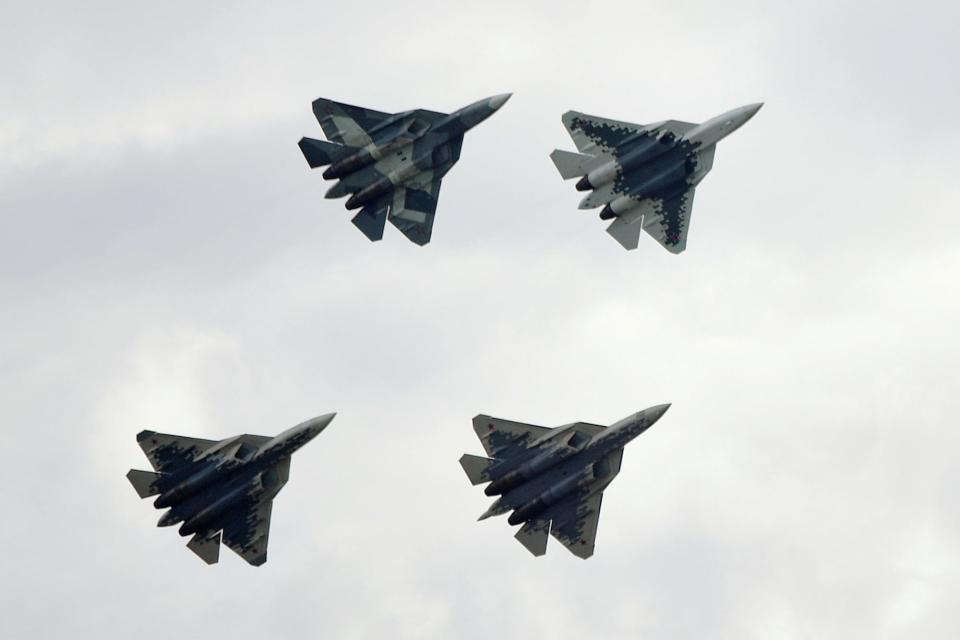 Four Sukhoi Su-57 fighter jets in the air against a grey sky.