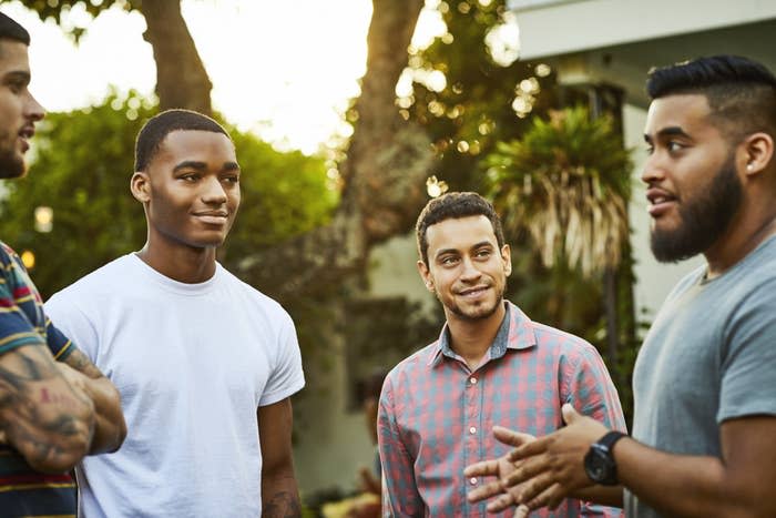 a group of guys standing together outside and talking