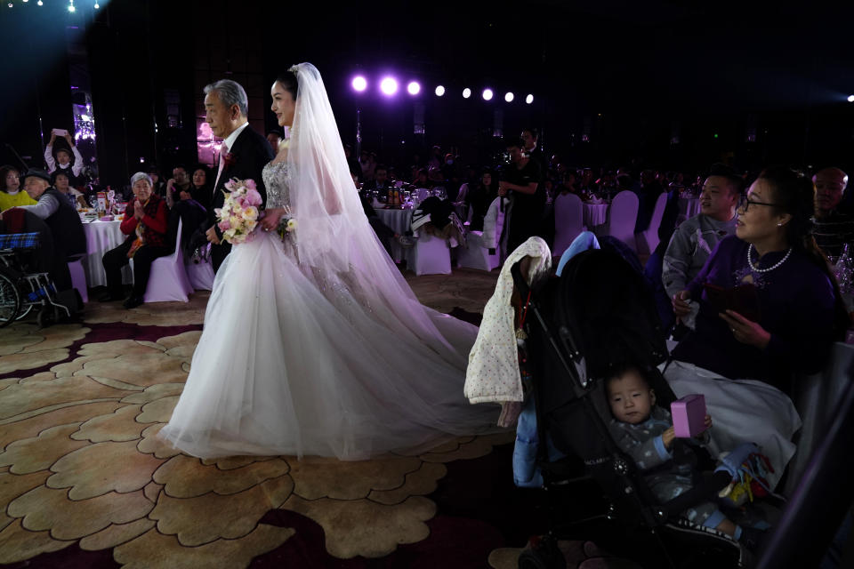 Bride Chen Yaxuan walks down the aisle with her father during an unmasked wedding banquet in Beijing on Saturday, Dec. 12, 2020. Lovebirds in China are embracing a sense of normalcy as the COVID pandemic appears to be under control in the country where it was first detected. (AP Photo/Ng Han Guan)