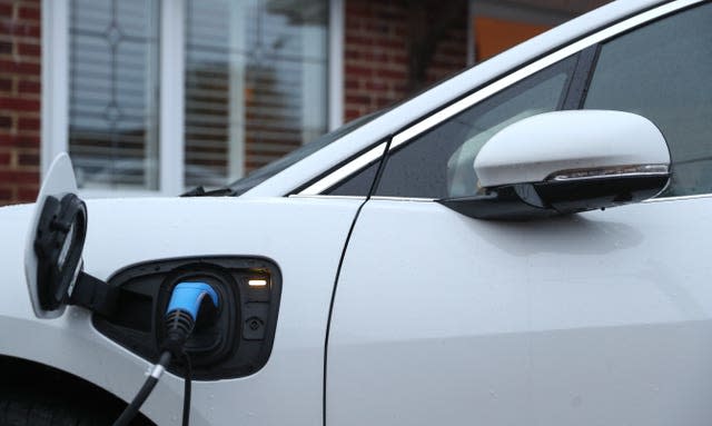 An electric charging cable connected to a Jaguar I-Pace electric car at a residential home.