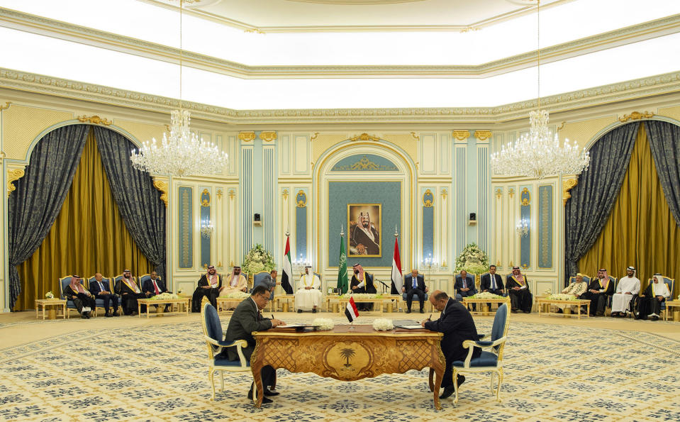 In this photo released by the Saudi Royal Palace, Yemeni Southern Transitional Council member and former Aden Governor Nasser al-Khabji, left, and Yemen's deputy Prime Minister Salem al-Khanbashi sign a power-sharing deal in Riyadh, Saudi Arabia, Tuesday, Nov. 5, 2019. Yemen's internationally recognized government signed a power-sharing deal with Yemeni separatists that are backed by the United Arab Emirates. A picture of Saudi Arabia's founder late King Abdul Aziz Al Saud hangs on wall. (Bandar Aljaloud/Saudi Royal Palace via AP)