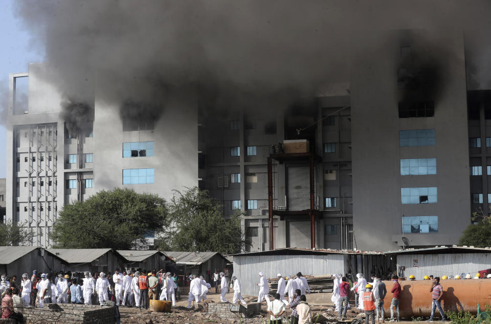 Employees leave as smoke rises from a fire at Serum Institute of India, the world's largest vaccine maker that is manufacturing the AstraZeneca/Oxford University vaccine for the coronavirus, in Pune, India, Thursday, Jan. 21, 2021. (AP Photo/Rafiq Maqbool)