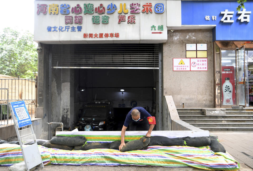 In this photo released by Xinhua News Agency, a man sandbags the entrance to an underground garage in Jinshui District of Zhengzhou, in central China's Henan Province, on Sunday, Aug. 22, 2021. Torrential rains in central China caused landslides, knocked out power and damaged houses, but no deaths were reported in a region where flooding killed more than 300 people last month, the government said Monday. (Hao Yuan/Xinhua via AP)