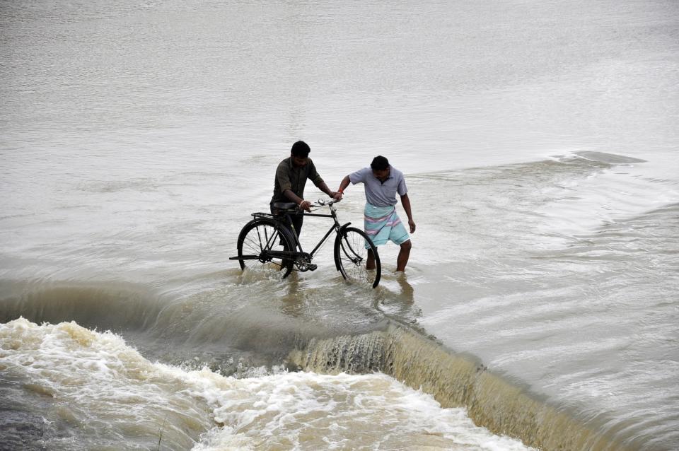 Men cross a flooded road after heavy rains caused by Cyclone Phailin at Gaghra village