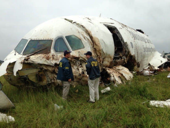 In this handout photo provided by the National Transportation Safety Board (NTSB), NTSB workers inspect the wreckage of a UPS cargo plane that crashed in a field outside of Birmingham-Shuttlesworth International Airport August 14, 2013 in Birmingham, Alabama.  The pilot and co-pilot died in the crash but no other injuries were reported.