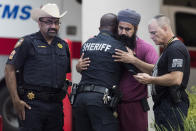 Mourners gather outside Memorial Hermann Hospital in Houston after Harris County Sheriff's Deputy Sandeep Dhaliwal was transported to the medical examiners office after he was shot and killed in the line of duty on Friday, Sept. 27, 2019. Dhaliwal was shot and killed while making a traffic stop Friday near Houston. (Brett Coomer/Houston Chronicle via AP)
