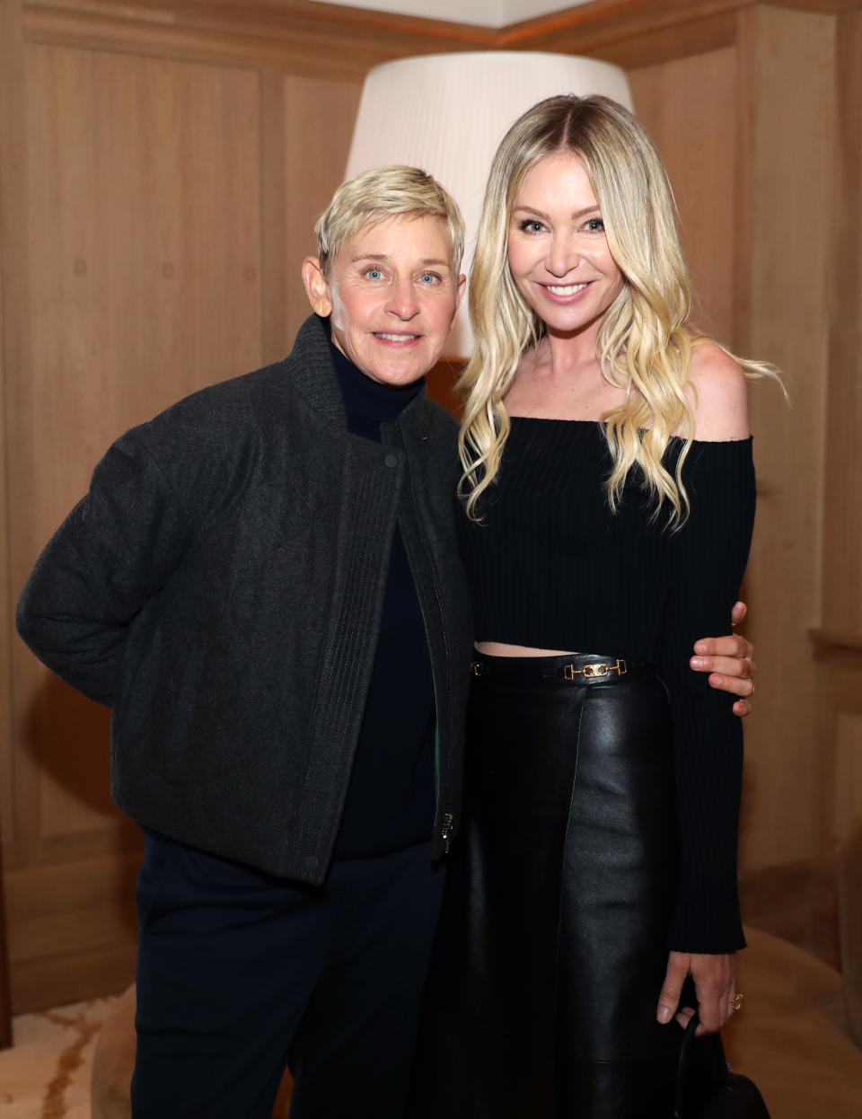 Two people posing for the camera.  One is wearing a black jacket and shirt, and the other is wearing a black off-shoulder top and skirt.