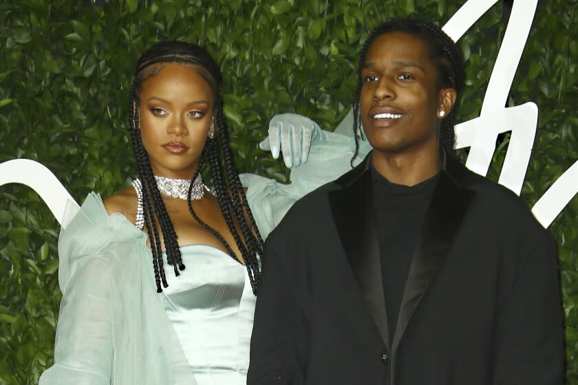 A woman and a man in formalwear posing in front of a leafy background