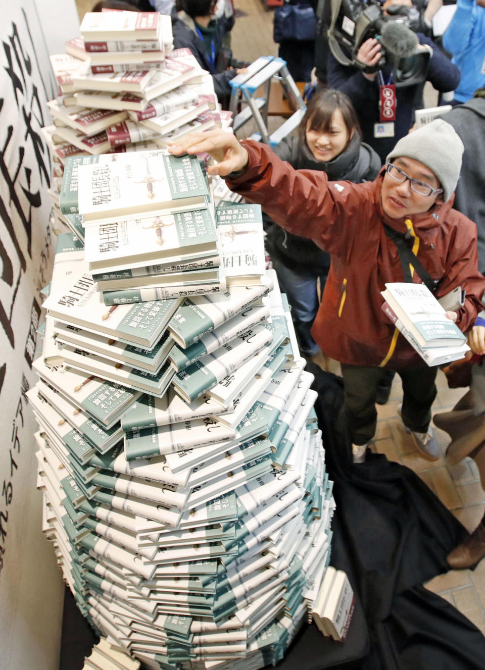 People buy copies of the new book written by Haruki Murakami at a book store in Tokyo shortly after midnight, Friday, Feb. 24, 2017. Murakami's new book "Kishidancho Goroshi," or "Killing Commendatore," is a two-part story about a 36-year-old portrait painter and the mysterious incidents that happen after his wife divorces him and he moves into an old house on a mountainside west of Tokyo. (Fumine Tsutabayashi/Kyodo News via AP)