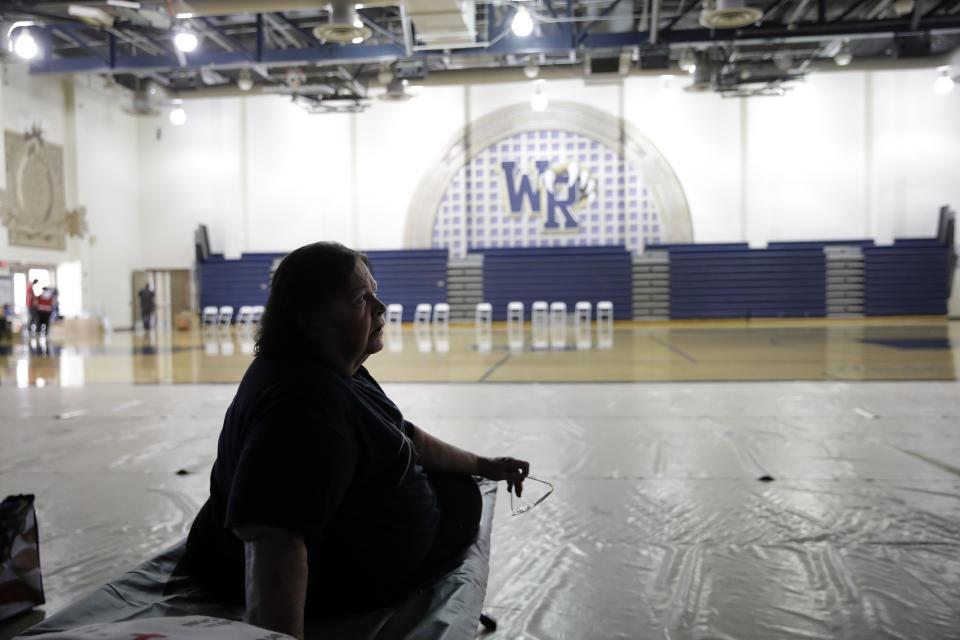Mary Lewis, an evacuee from the Tick Fire, sits on a cot at a shelter inside the West Ranch High School gym Friday, Oct. 25, 2019, in Santa Clarita, Calif. (AP Photo/Marcio Jose Sanchez)