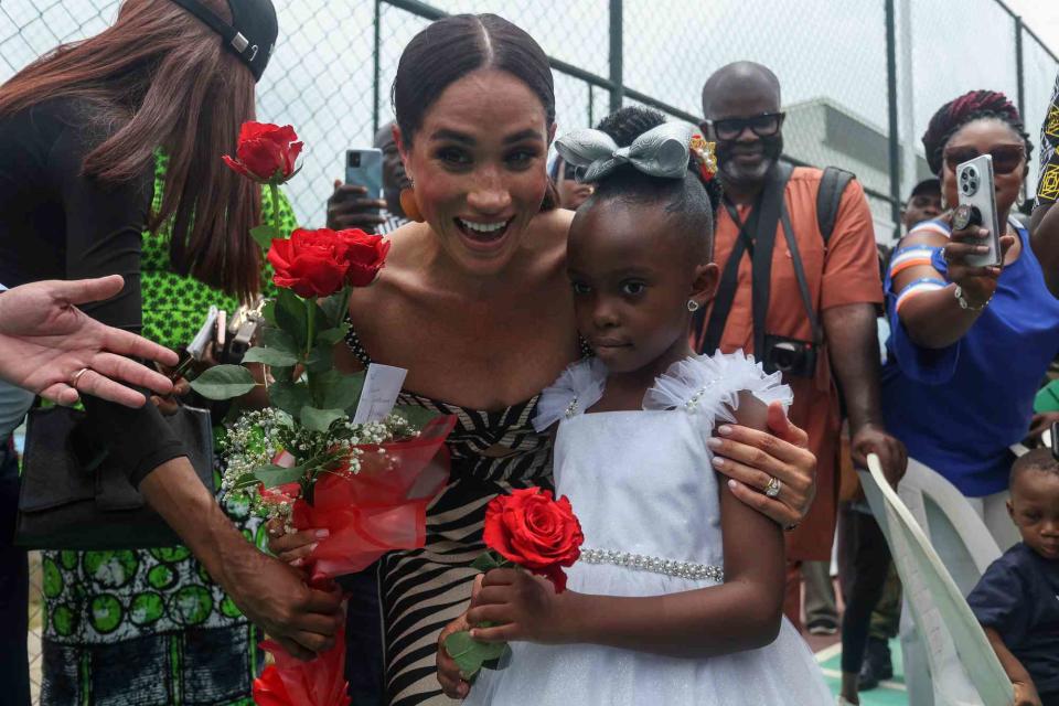 <p>KOLA SULAIMON/AFP via Getty</p> Meghan Markle accepts flowers from Royalty Ojeh during a sitting volleyball match at Nigeria Unconquered, a local charity organisation that supports wounded, injured, or sick service members, in Abuja on May 11, 2024. 