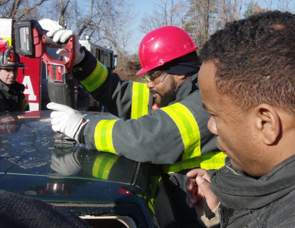 Praia Cape Verde Deputy Fire Chief Ronaldo Varela uses a cutting tool to shear off the roof of a Volkswagen Golf during training with the Brockton Fire Department on Thursday, Nov. 30, 2023. At right, watching Varela's progress, is Brockton Firefighter and Cape Verde native Helio Lima.