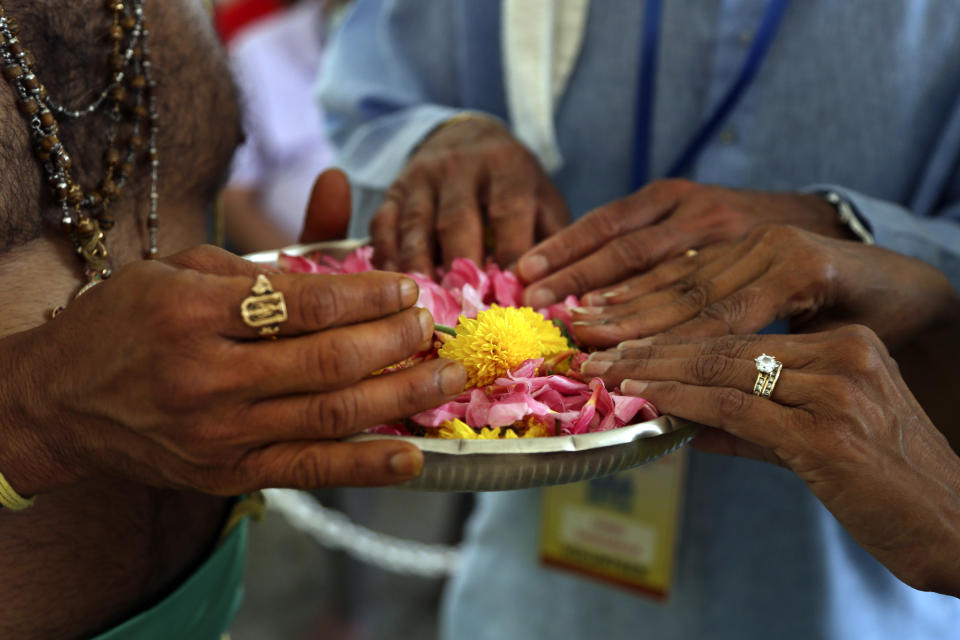 Hindu priest Gopala Dhattar, left, gives blessings to Pandu Tadikamalla, center, and his wife, Rama Tadikamalla, right, as they rest their hands on a bed of flower petals during the Maha Kumbhabhishekam, a five-day rededication ceremony at the Sri Venkateswara Temple in Penn Hills, Pa, Friday, June 25, 2021. Built in the 1970s, the Sri Venkateswara Temple is the oldest major Hindu temple in the country. Maha Kumbhabhishekams occur about every 12 years and involve ceremonies to reenergize the temple and its deities. (AP Photo/Jessie Wardarski)