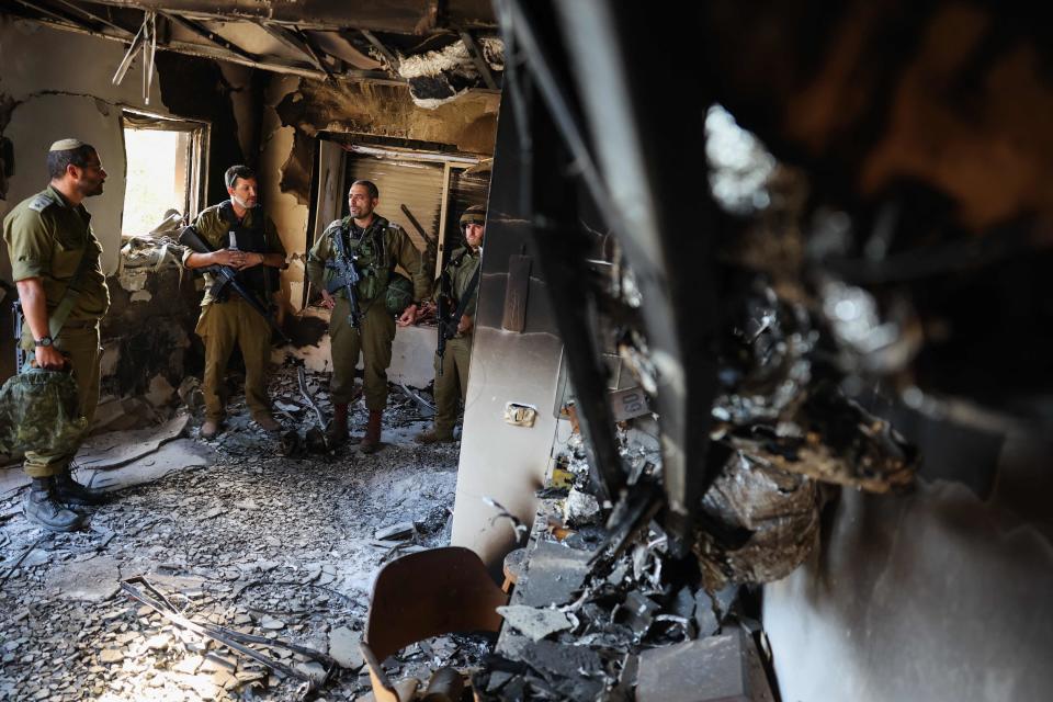 Members of the Israeli army pray in memory of a fellow soldier killed on October 8 during an attack by Palestinian militants, as they inspect the damage in kibbutz Be' eri near the border with Gaza on October 17, 2023.