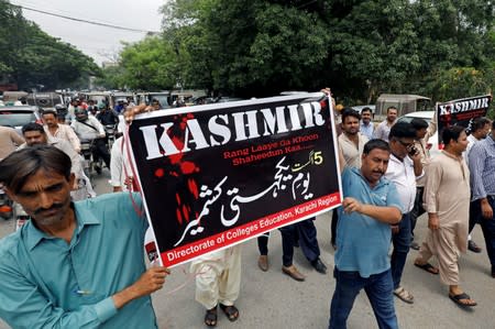 Demonstrators hold signs and chant slogans as they march in solidarity with the people of Kashmir, during a rally in Karachi