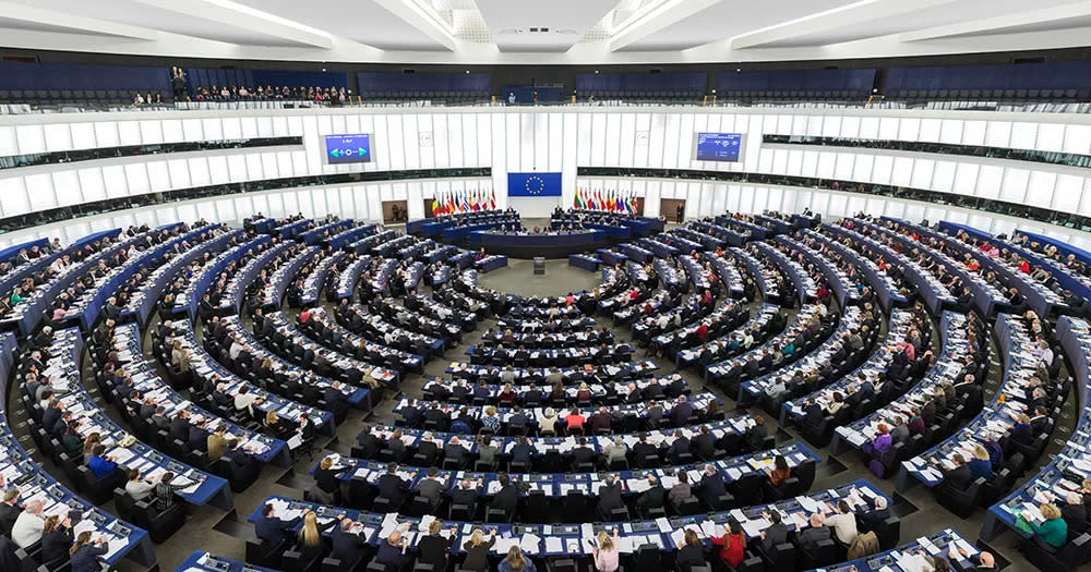 Inside the European Parliament in Strasbourg. The image shows a large room with curved rows of seats and curved white walls.